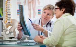 Person sitting in a clinic receiving a gentle spinal adjustment from a chiropractor.