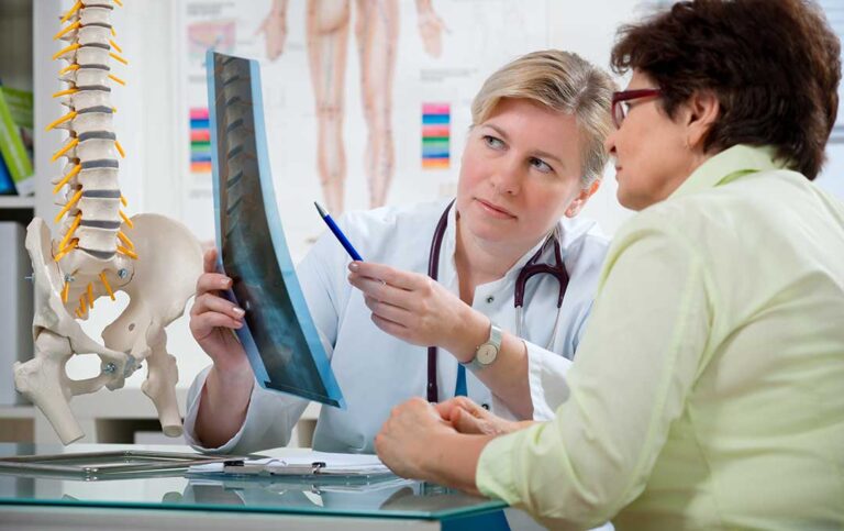 Person sitting in a clinic receiving a gentle spinal adjustment from a chiropractor.